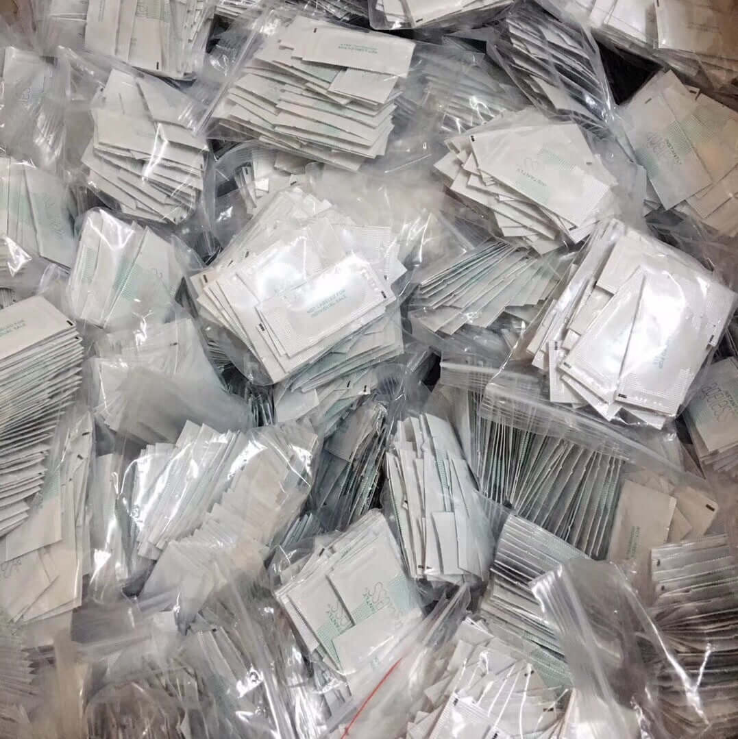 A large pile of individual eye cream sample packets in clear plastic bags, showcasing diverse packaging.