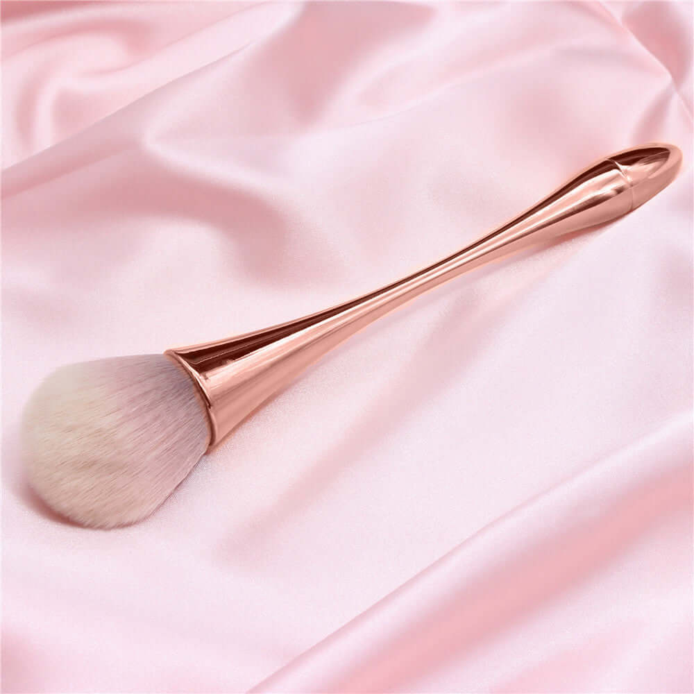 High-quality rose gold makeup brush resting on pink satin, designed for flawless application with no streaks.