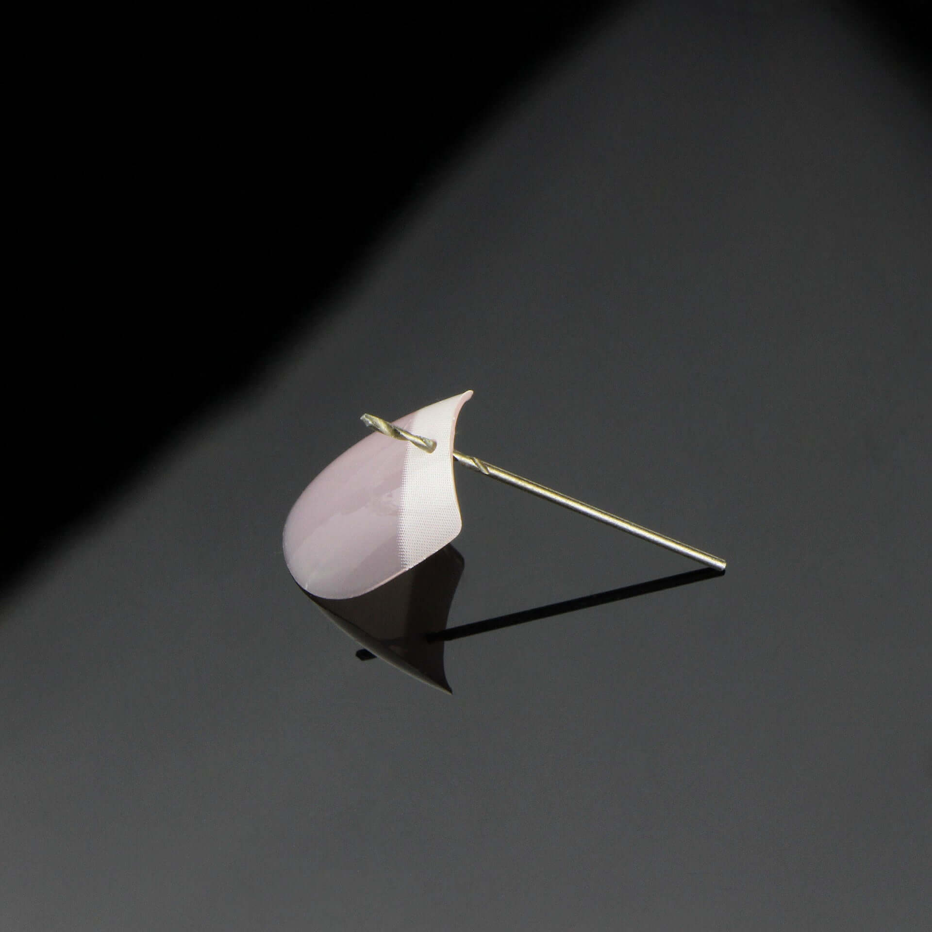 Nail art charm accessory featuring a pink and white design on a gold pin for DIY nail art projects.