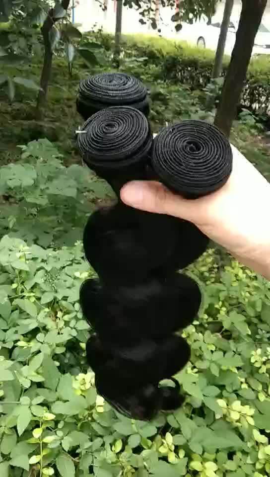 Body wave Brazilian hair curtain in natural color held in a hand, showcasing smooth, real human hair bundles.