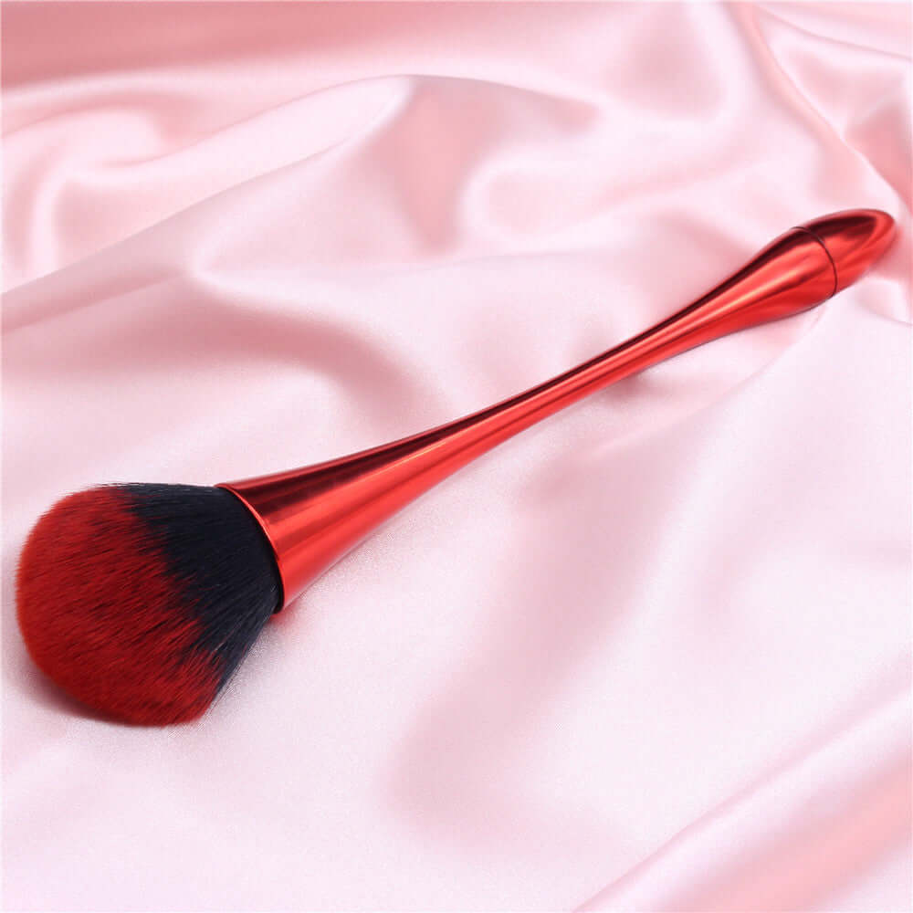 Red professional makeup brush with a special shape for flawless application on a satin fabric background.